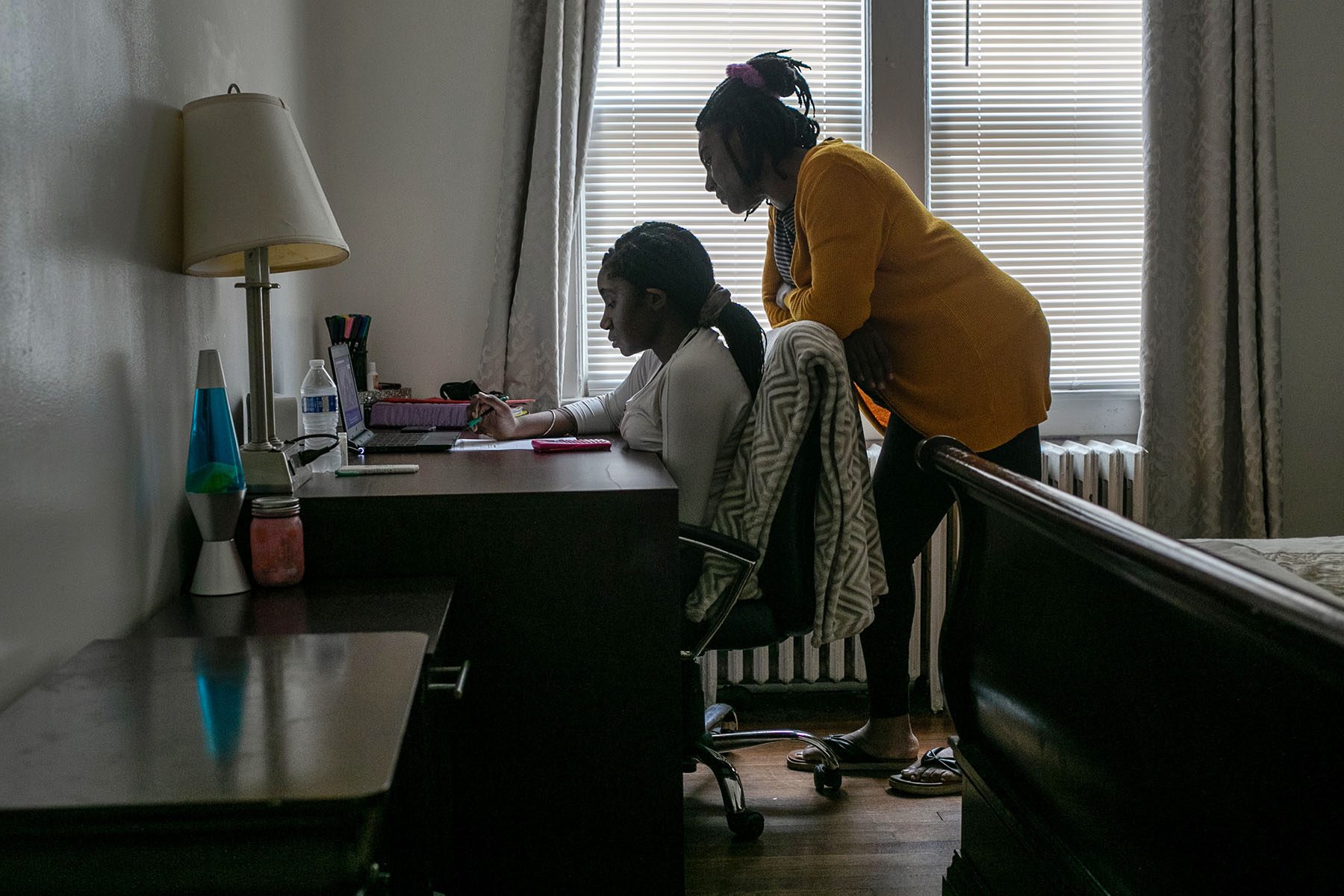 A student takes part in remote learning with the help of her mother at home.