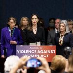 Angelina Jolie stands with women senators at a lectern that says 