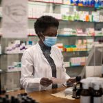 Woman pharmacist with face mask working in a drug store.