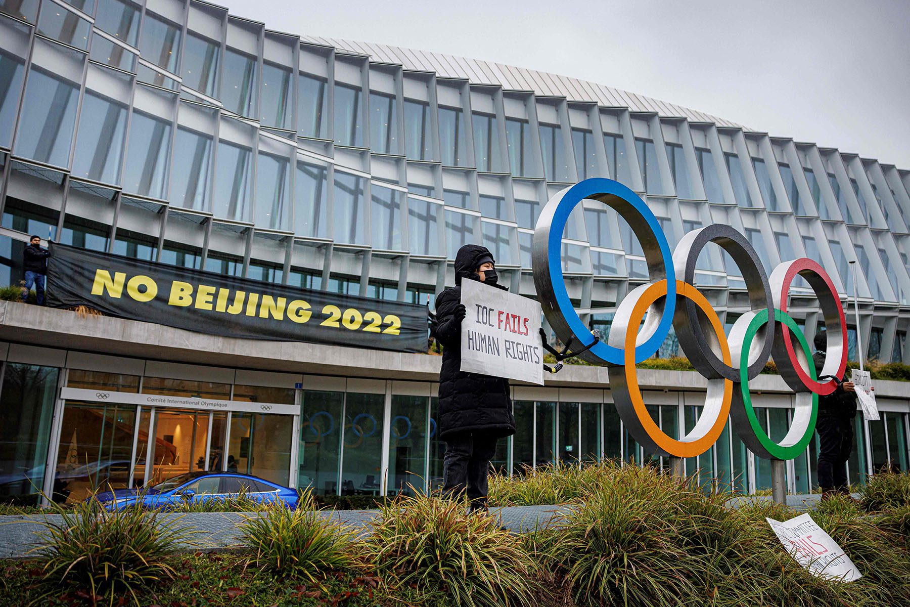 Activists hold banners that read "No Beijing 2022" and "IOC Fails Human Rights" in front of the IOC headquarters.