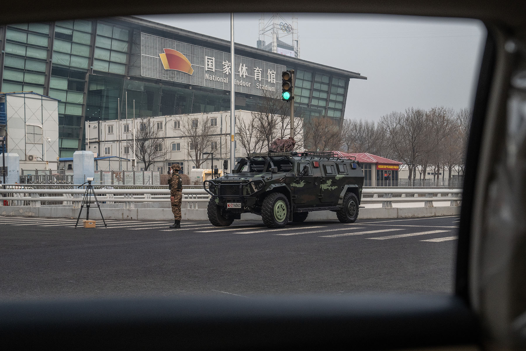 A soldier stands near an armored vehicle on an empty street.