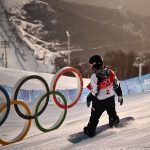 Chloe Kim is seen snowboarding near Olympic rings.