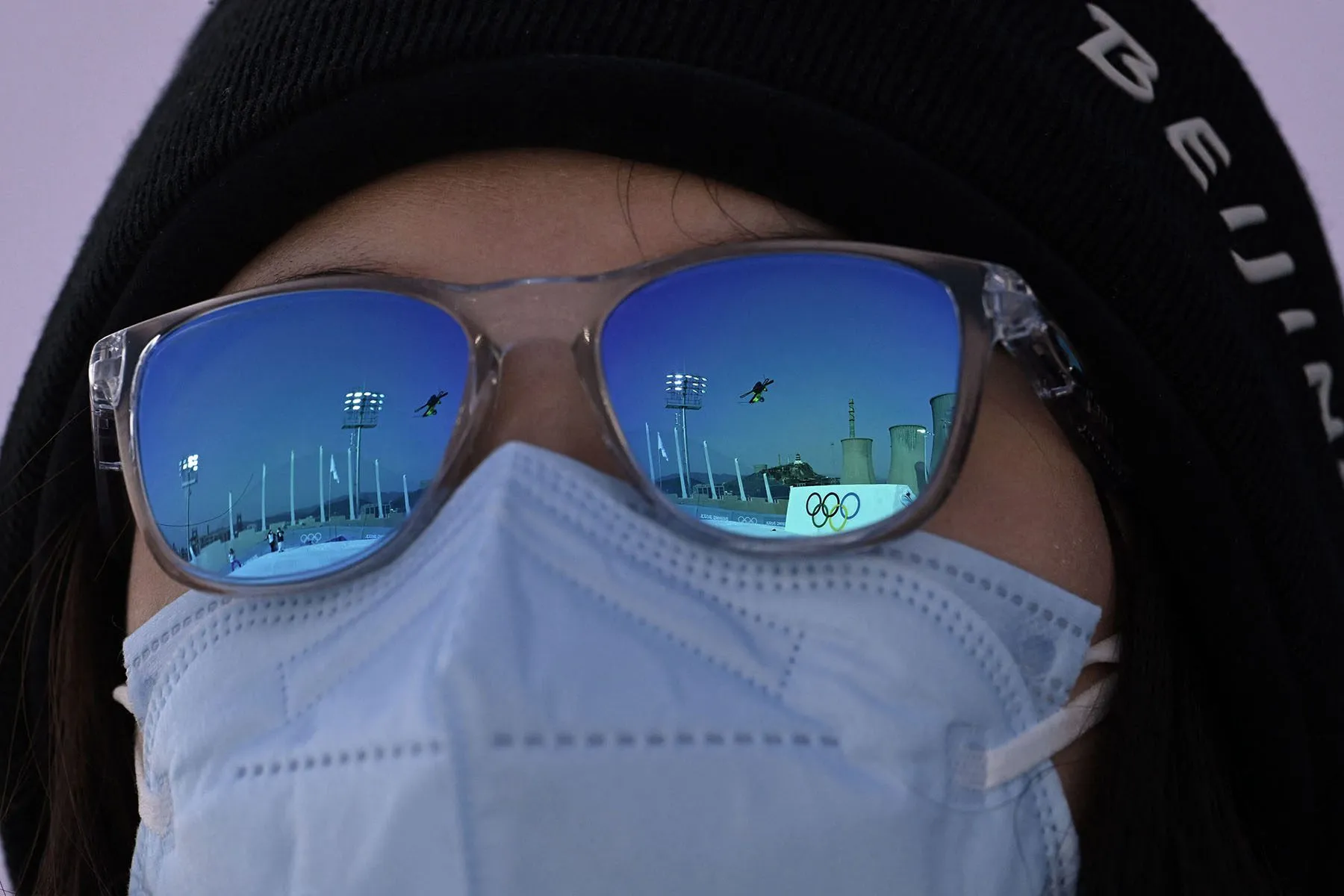 A skier is reflected in a volunteer's sunglasses as they watch the practice.