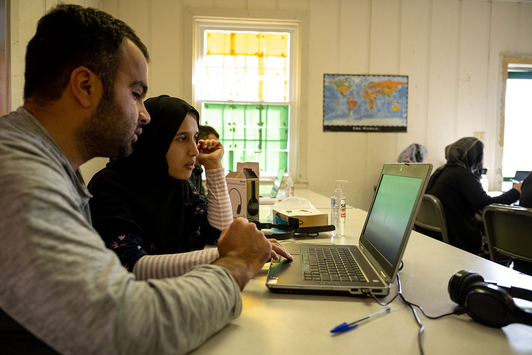 Afghan doctors study on shared laptops in a makeshift classroom.