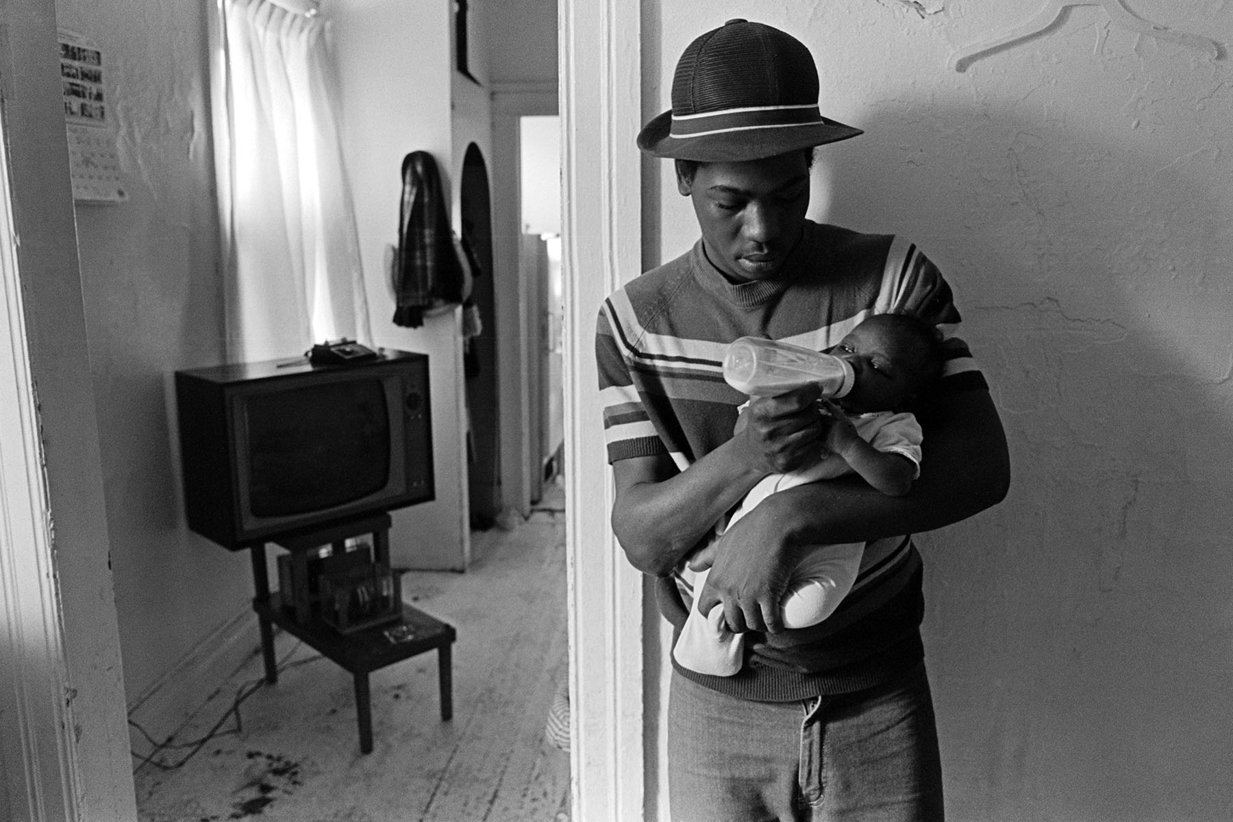 A father feeds his baby in his Detroit home.