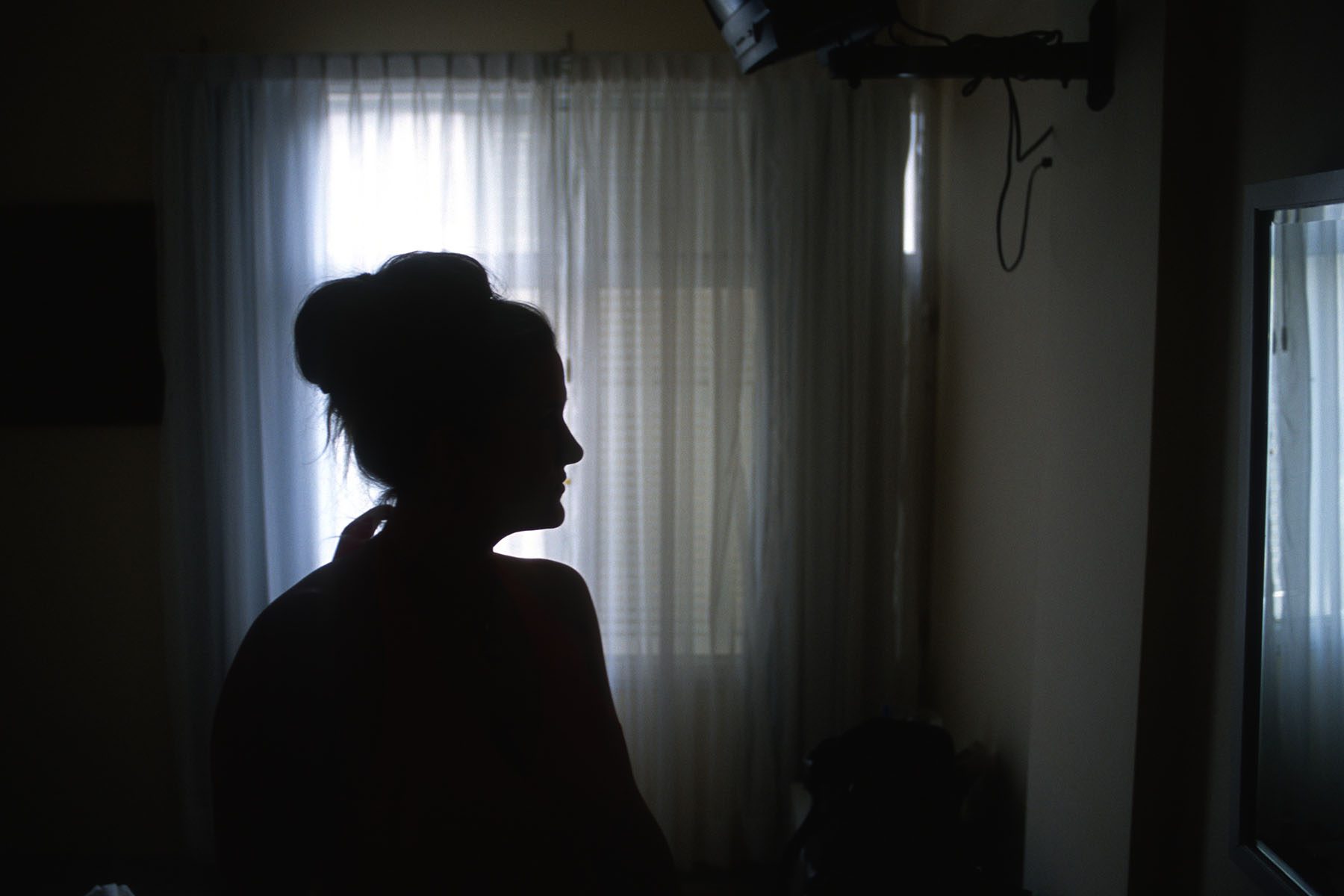 Silhouette of a woman in a room near the window.