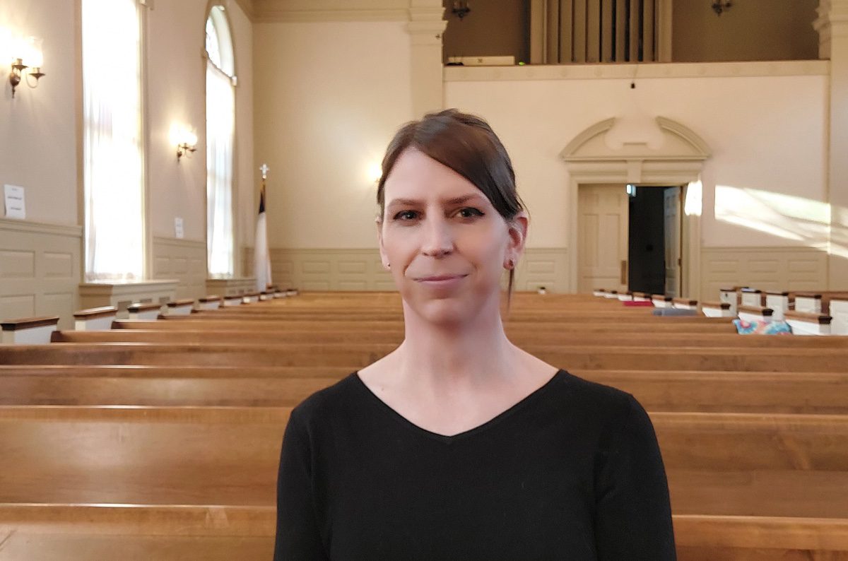 Kalie Hargrove stands in front of pews in a church