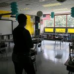 A woman superintendent looks over an empty classroom.