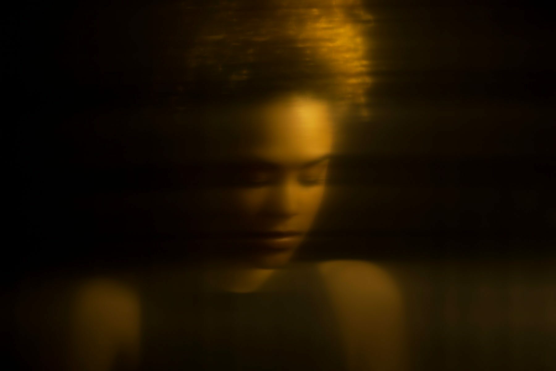 Distorted portrait of young woman behind glass.