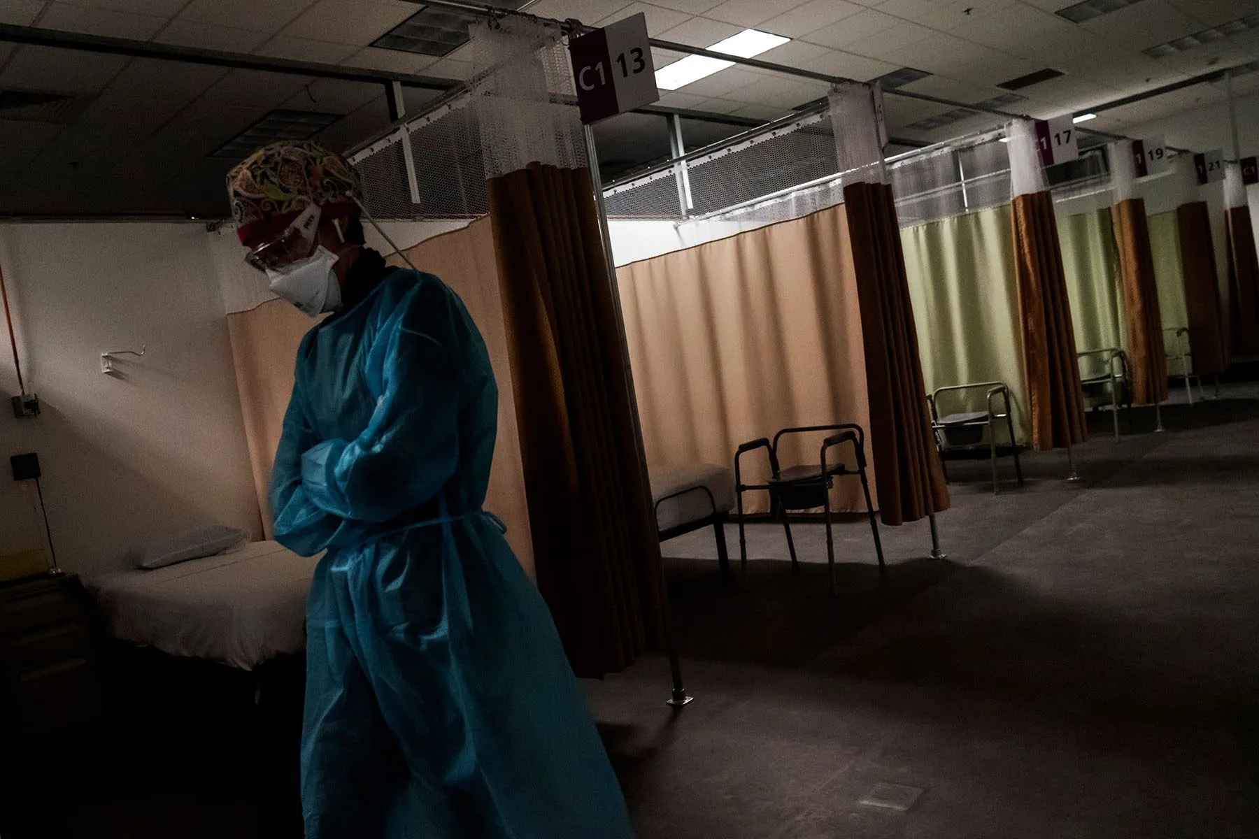 A travel nurse walks down an empty hallway in a field hospital.