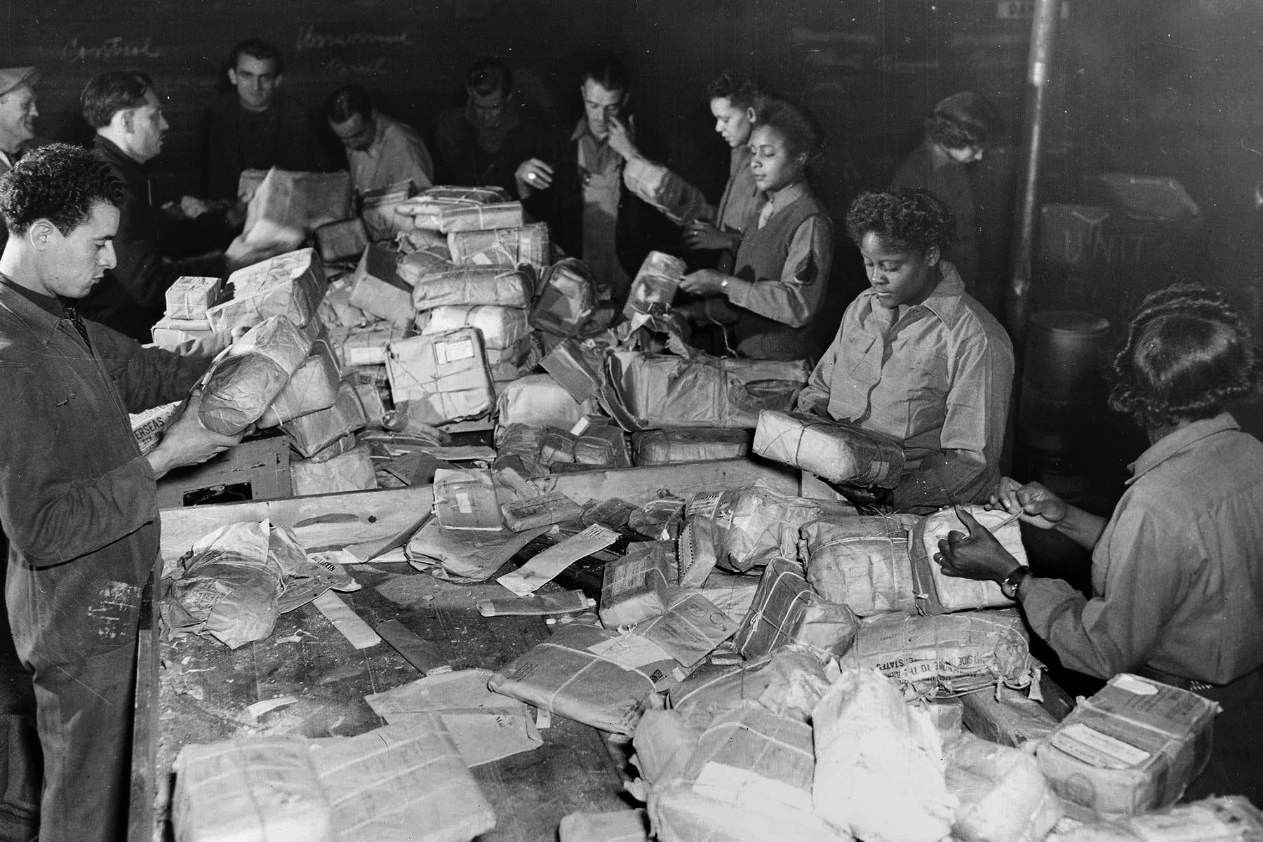 Members of the 6888th battalion and postal employees sort mail.