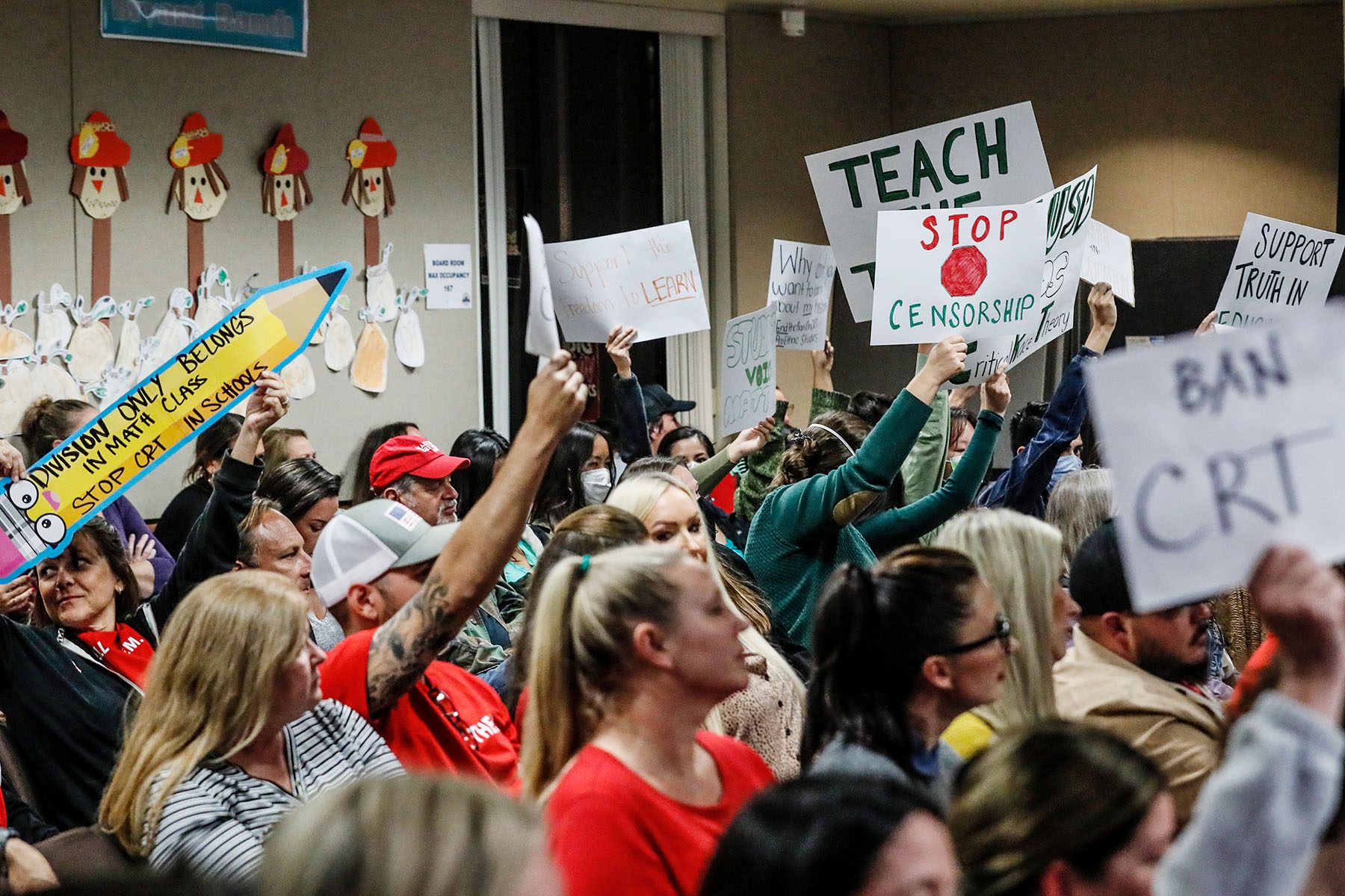 Parents attend a school board meeting to discuss Critical Race Theory. Some hold signs that read "Stop Censorship," "Ban CTR," "Support truth in Education."