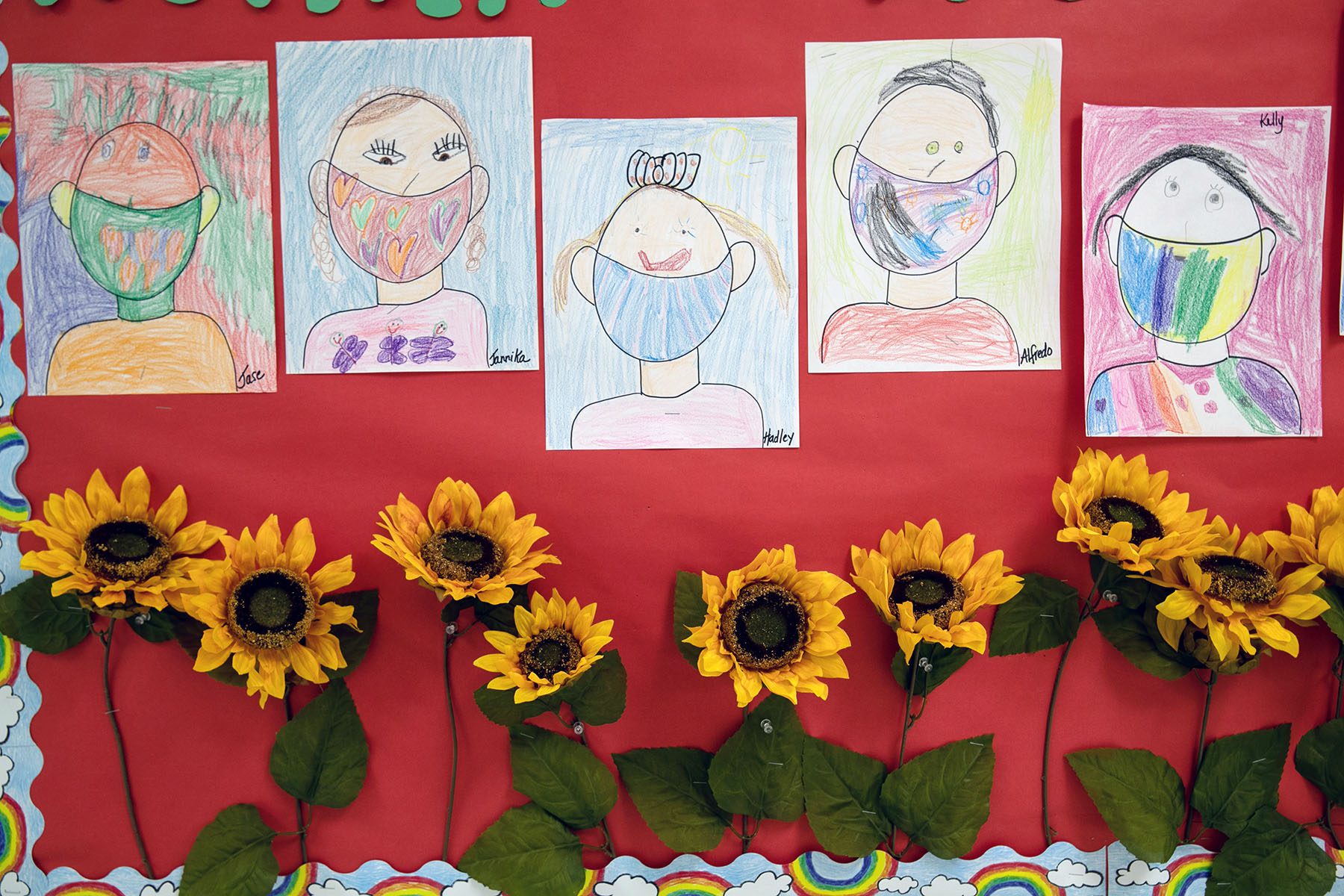 Drawings of children wearing masks adorn a hallway.