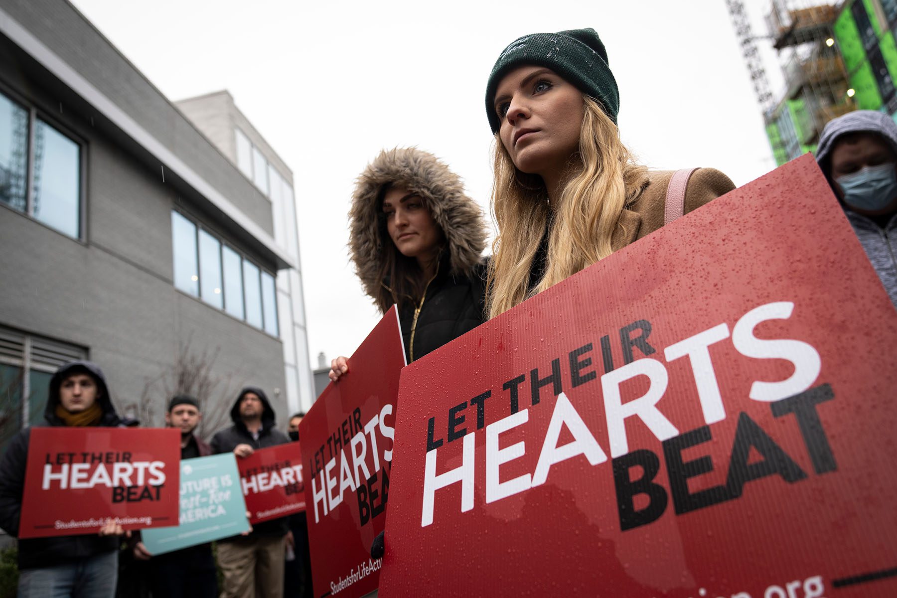 Anti-abortion activists hold signs that read "Let Their Hearts Beat" outisde a Planned Parenthood.