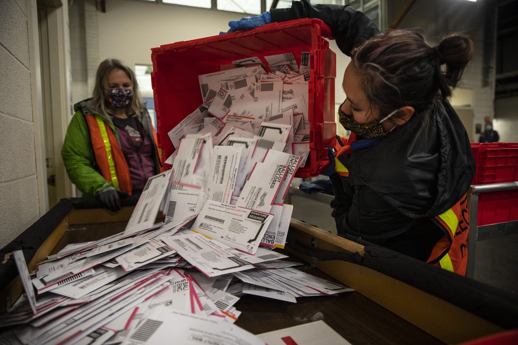 An election worker dumps ballots out of a big red bin