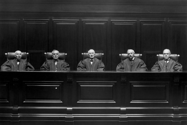 View of a courtroom interior, circa 1890. Five robed judges are shown seated at the bench.