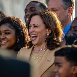 Vice President Kamala Harris smiles as she takes a picture with students.