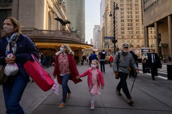 A family wears face masks as they walk through New York City.