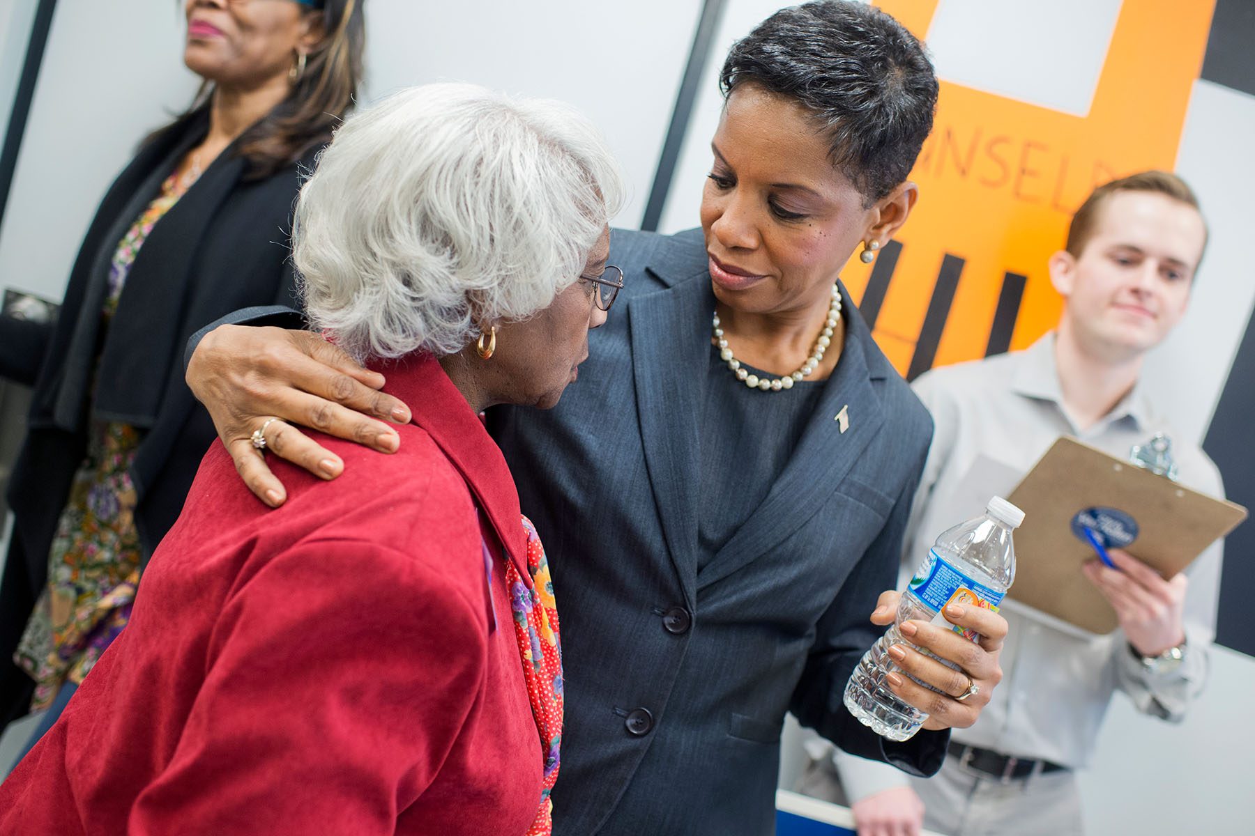 Donna Edwards puts her arm around an older woman as they speak.
