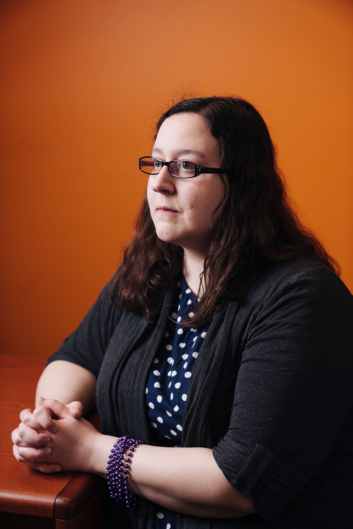 Julia Bascom poses for a portrait against a bright orange wall.