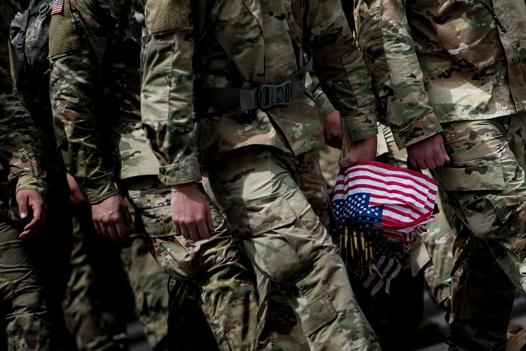 Soldiers holding american flag walk together in a tight group.