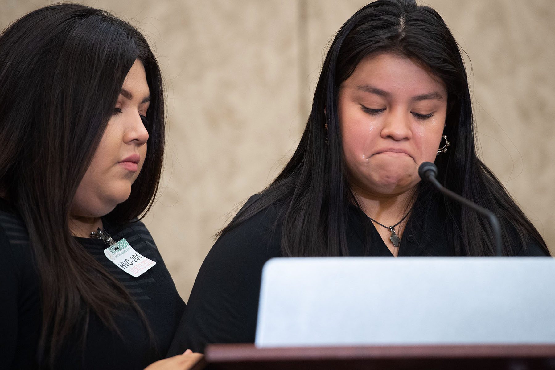 Mayra Guillen looks down at the podium as a tearful Lupe Guillen speaks into a microphone during a press conference.