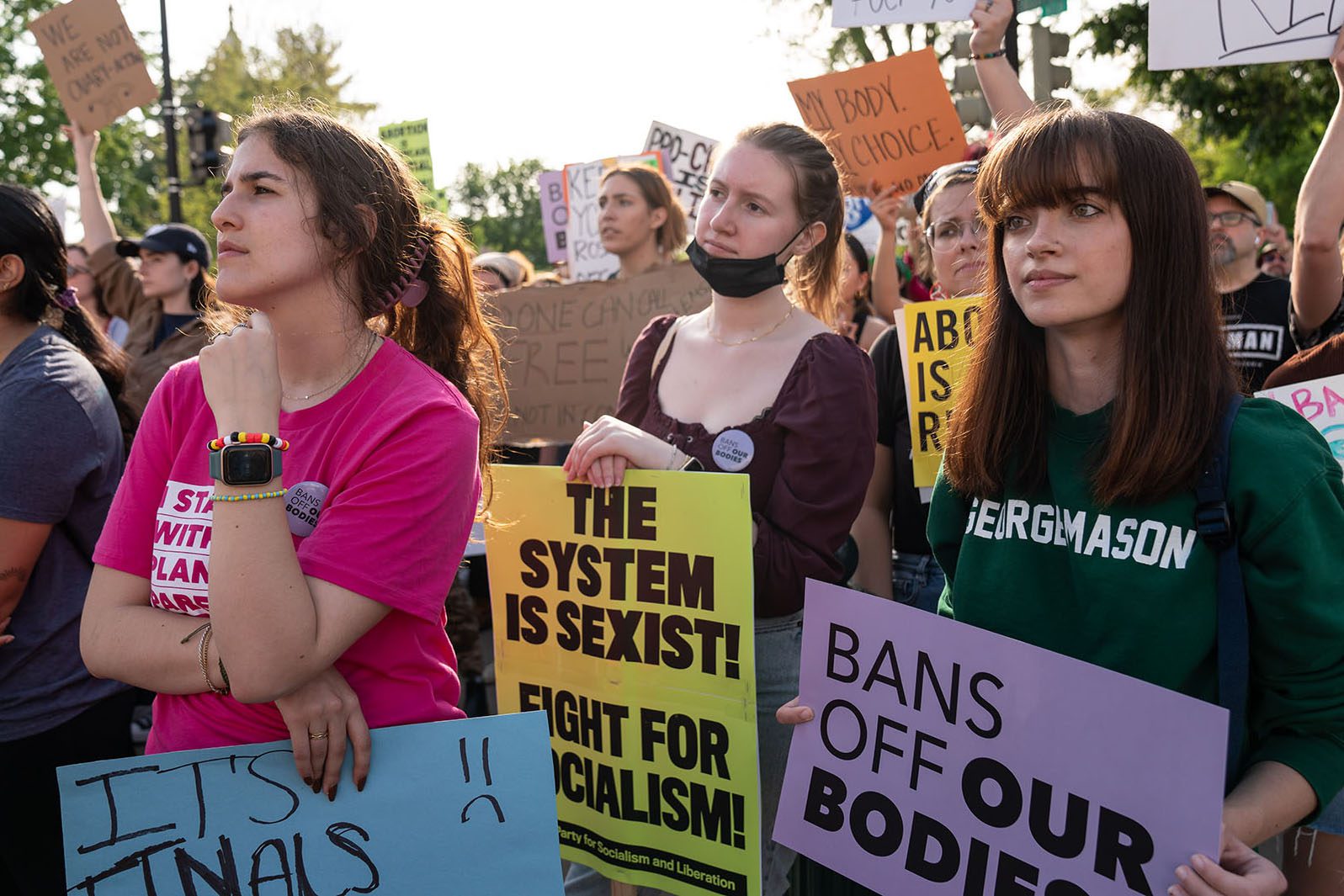 Demonstrators hold signs that read "the system is sexist! fight for socialism," "bans off our bodies" and "my body, my choice" as they demonstrate in front of the Supreme Court.