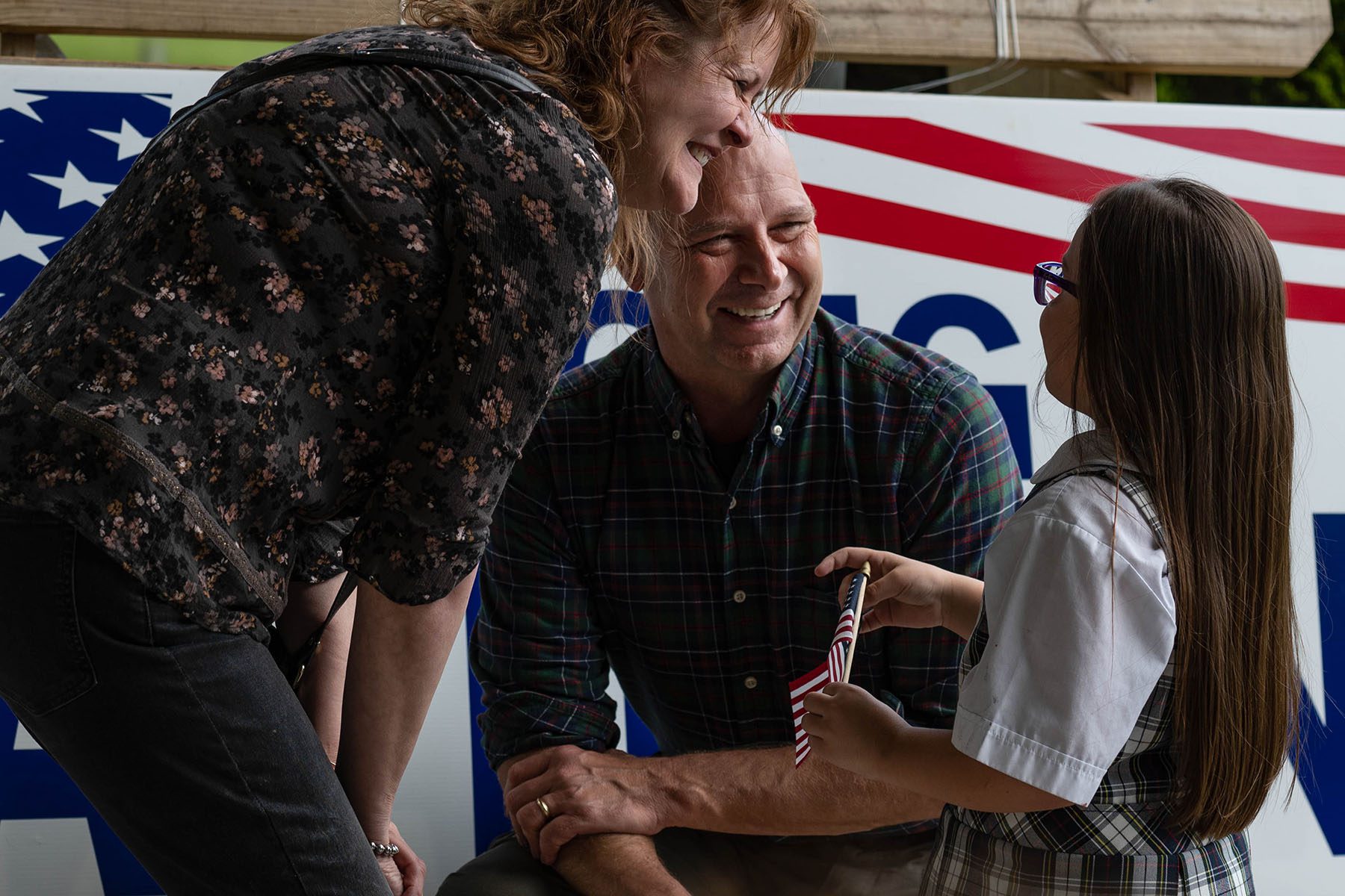 Doug Mastriano and his wife Rebecca smile as they speak to a child holding a small American flag.