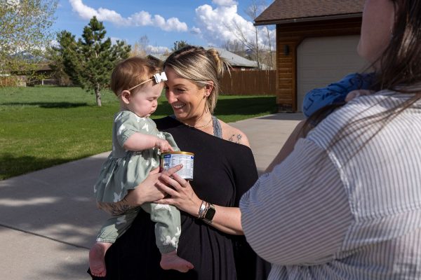 Mollie Wetzel nuzzles her 9 month old Olivia as they receive a can of baby from Alexis Adams.