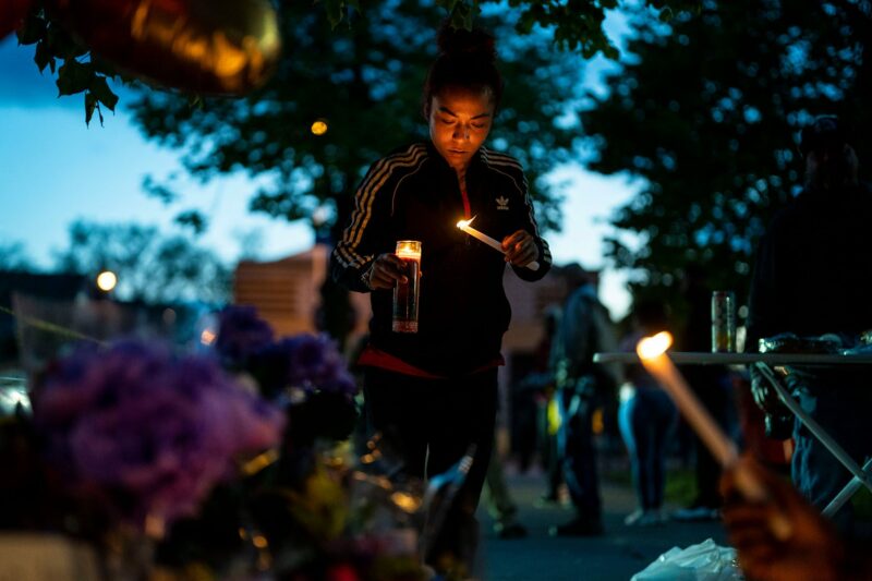 Alexis Rodriguez lights candles in front of a memorial for the Buffalo mass shooting.