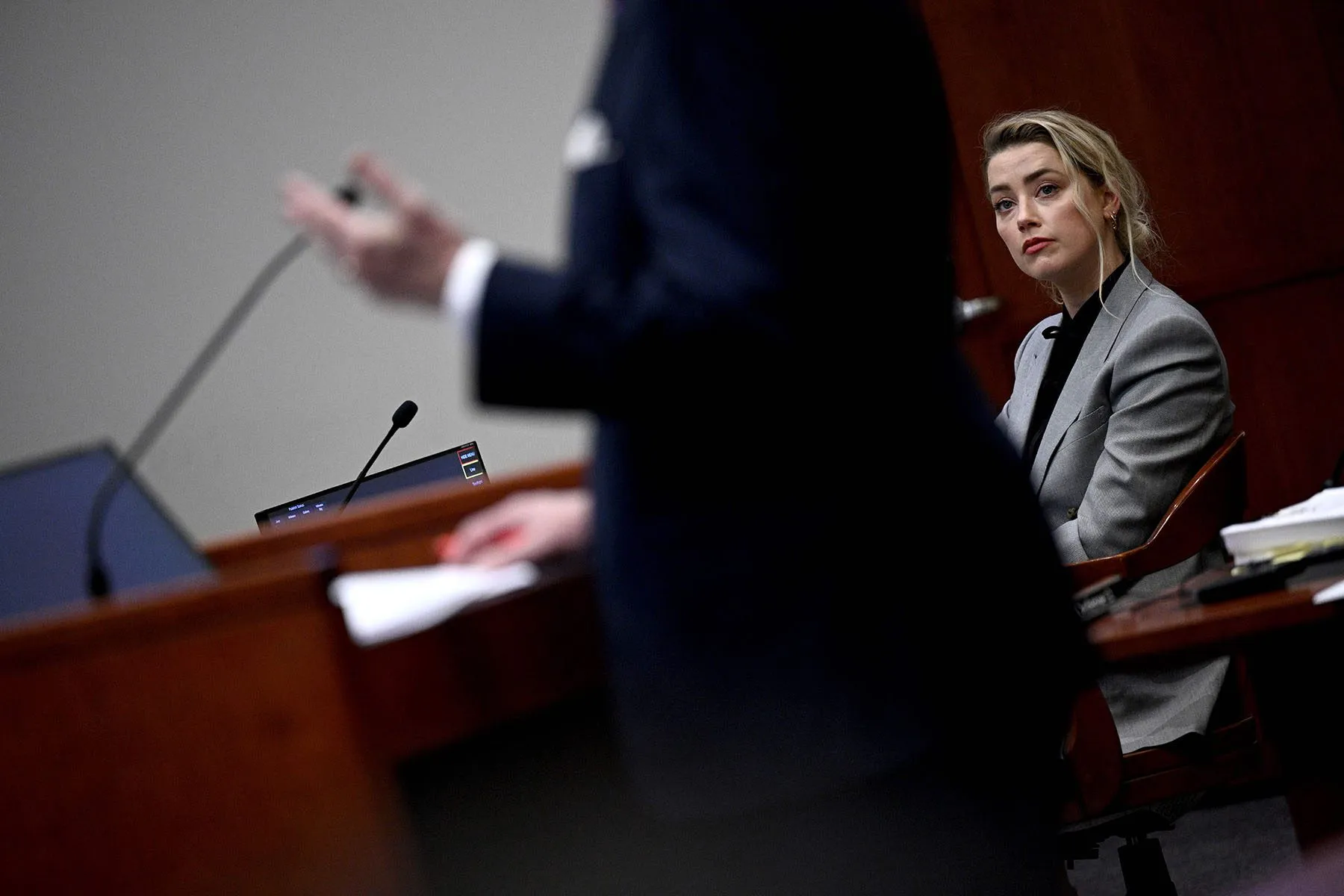 Amber Heard listens while a person in the foreground speaks.