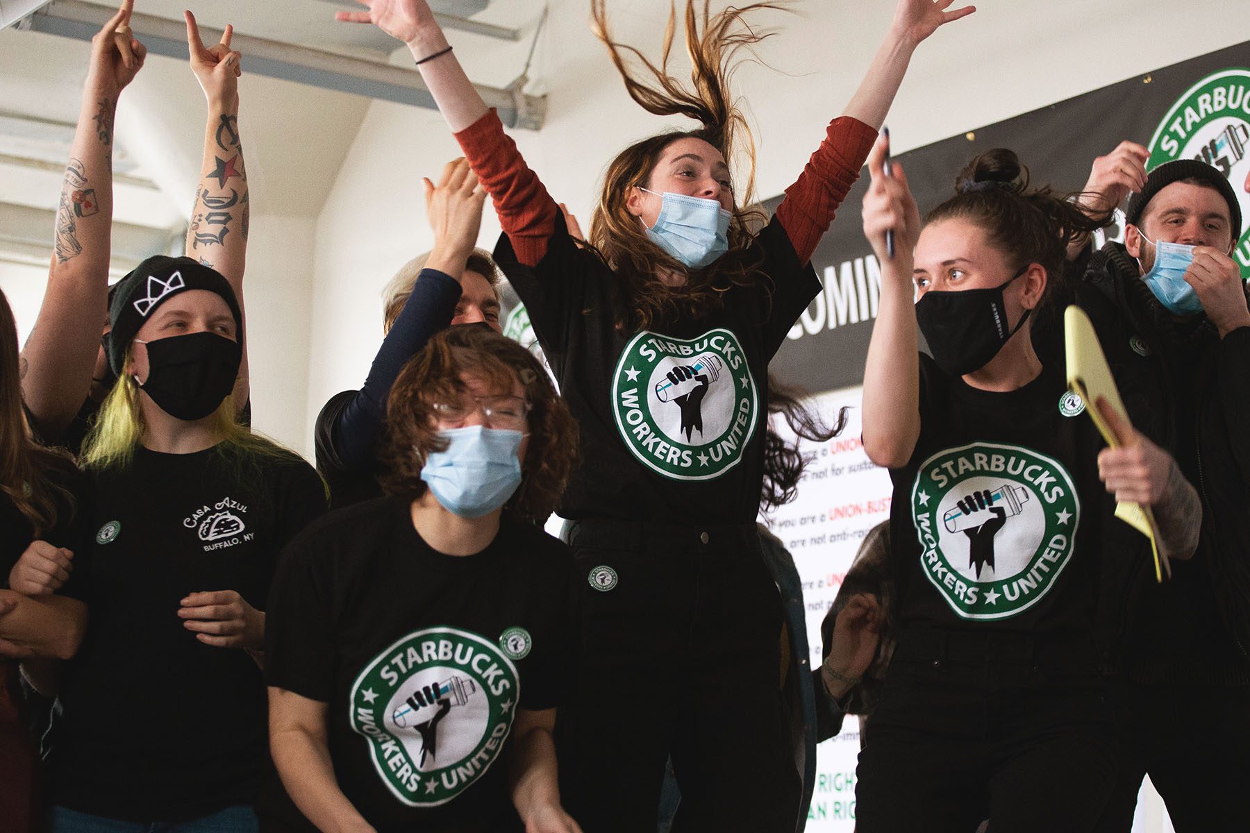 Starbucks employees jump up in the air and cheer during a viewing of their union election.