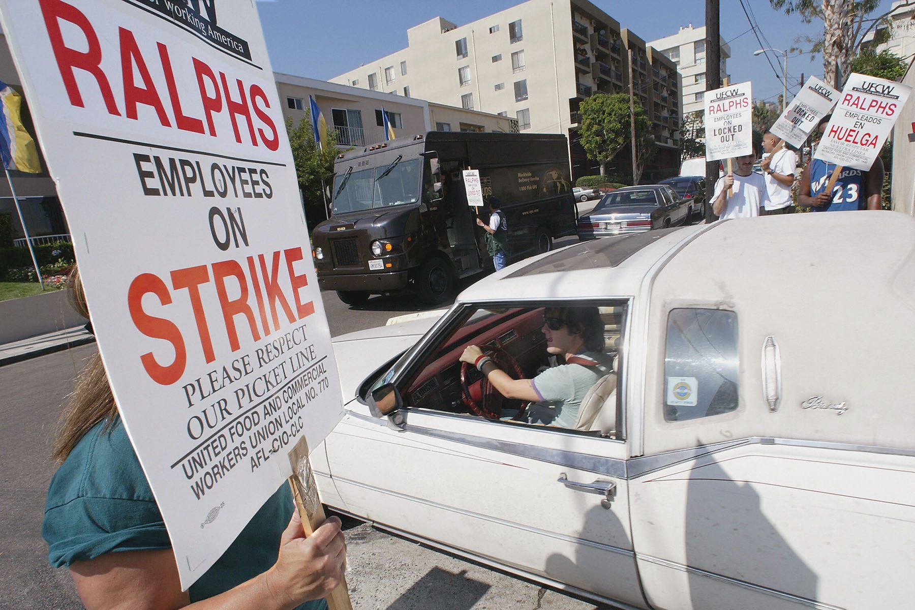 Un client passe devant des grévistes alors qu'il quitte un supermarché Ralphs. Les travailleurs brandissent des pancartes sur lesquelles on peut lire « Employés de Ralphs en grève, veuillez respecter notre ligne de piquetage ».