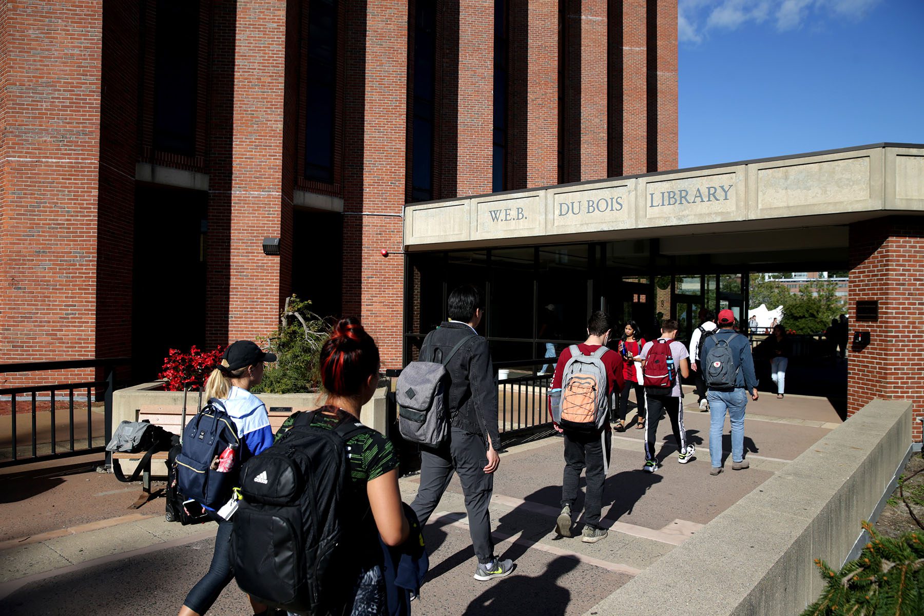 Students walk on the UMass Amherst campus near W.E.B. Dubois Library