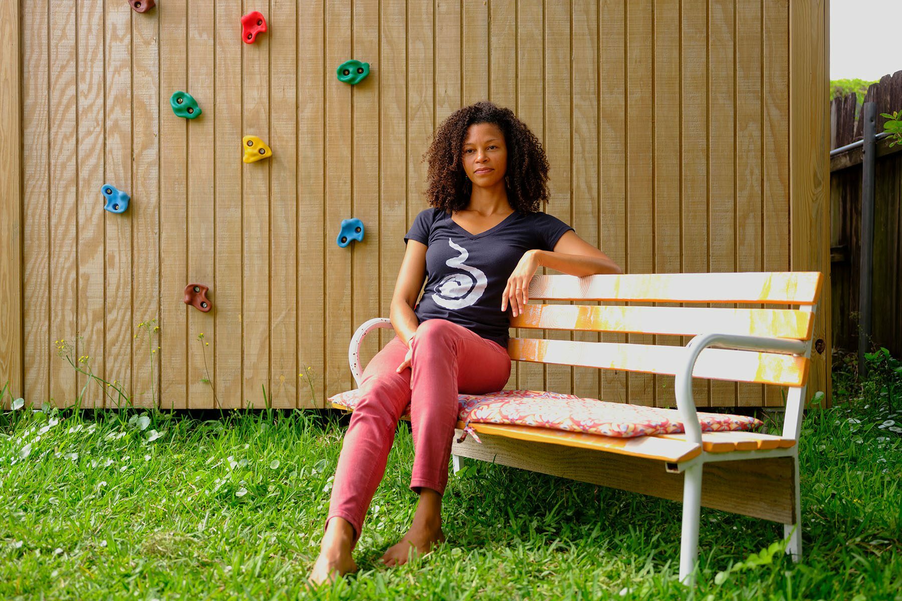 Malaika Ludman smiles slightly as she sits on a bench in her backyard.