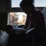 Silhouette of Woman Holding Newborn Son While Sitting On Chair In a Hospital