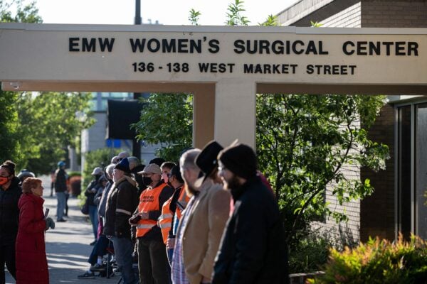 Anti-abortion rights demonstrators and clinic escorts stand in front of the EMW Women's Surgical Center.
