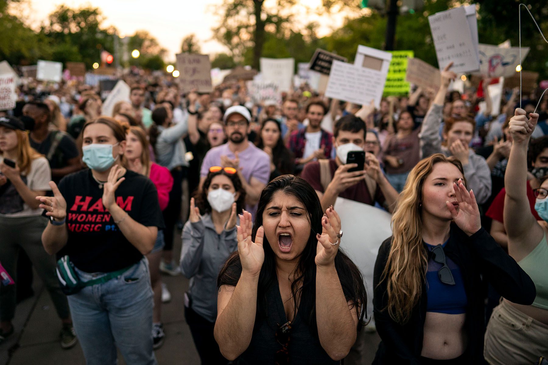 A large group of demonstrators chant and clap.