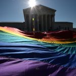 A giant LGBTQ+ pride flag is seen in front of the Supreme Court.