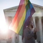 A supporter of same-sex marriage holds a pride flag near the Supreme Court.