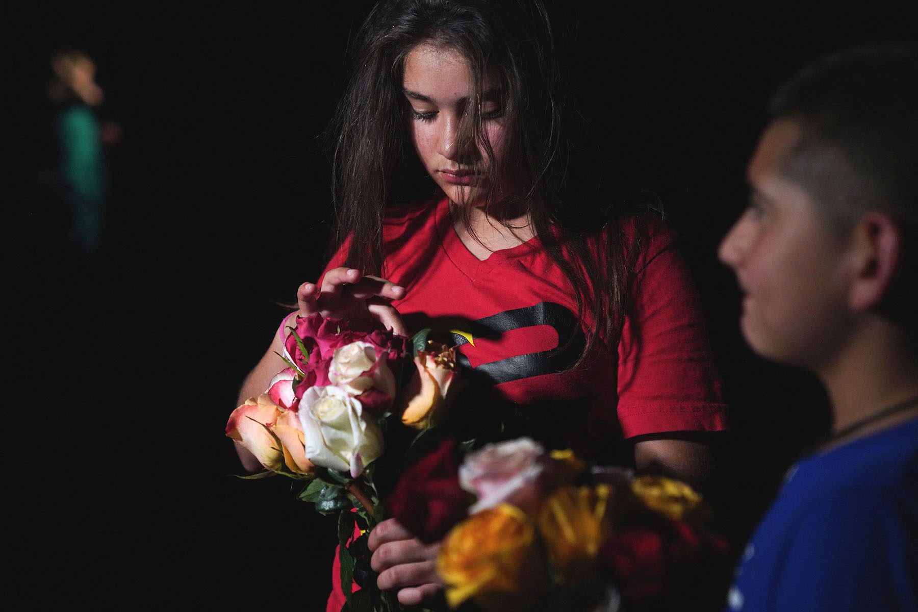 A young girl holds flowers as people gather to mourn the victims of the Uvalde shooting.