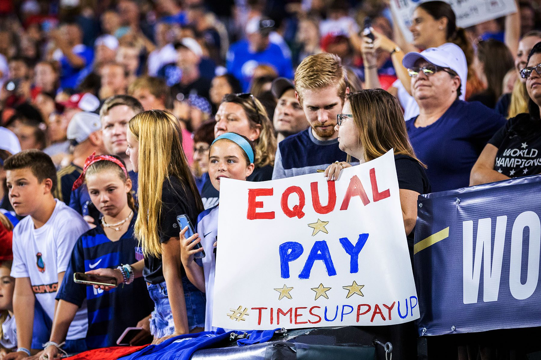 A fan holds up a sign that says "Equal Pay Times Up Pay Up" in support of the United States Women's National Team fight for equal pay.