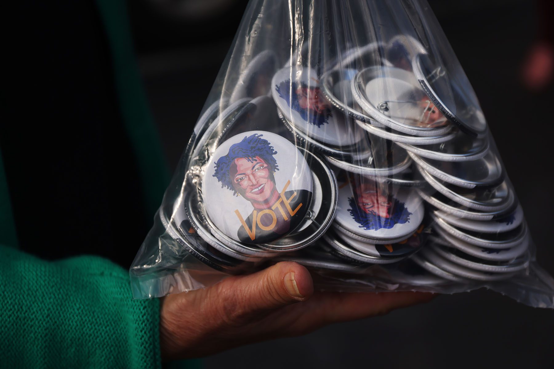 Pins with the face of Stacey Abrams at are handed out at a rally.