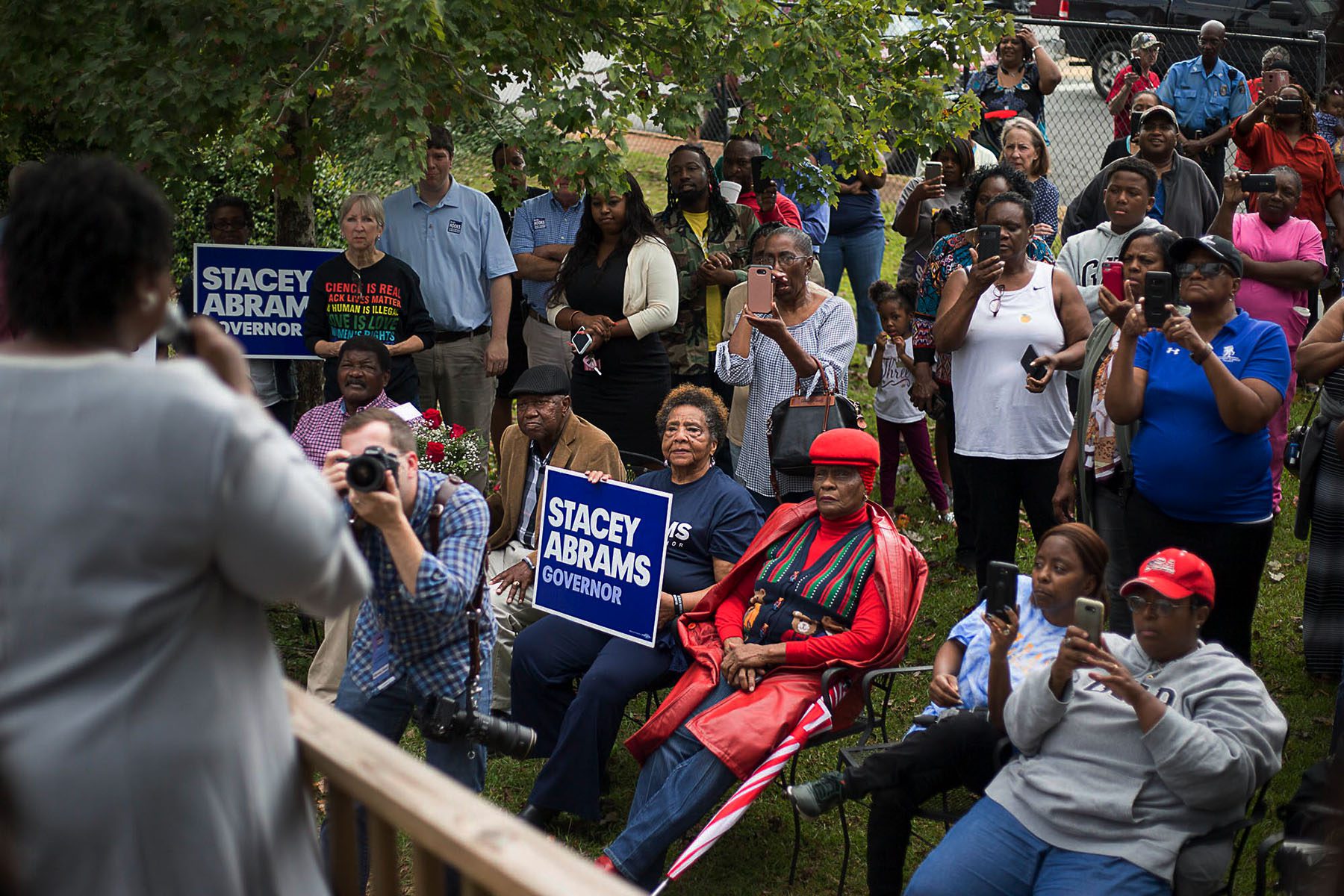 People take pictures and videos of Stacey Abrams as she speaks from the front porch of a small restaurant.