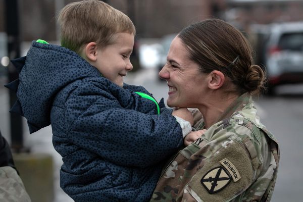 A mother embraces her young son after coming home from Afghanistan. They are both facing each other and smiling.