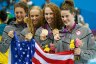 swimmers Allison Schmitt, Dana Vollmer, Shannon Vreeland and Missy Franklin celebrate after winning the gold medal by holding a U.S. flag and flower bouquets.