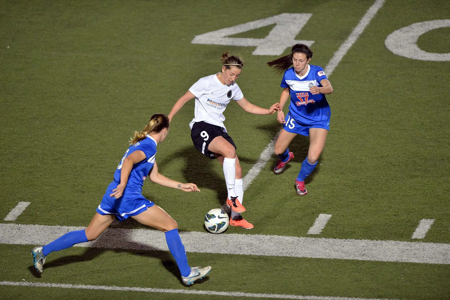 Portland Thorns FC forward Danielle Foxhoven moves the ball up field between FC Kansas City defenders Erika Tymrak and Courtney Jones.