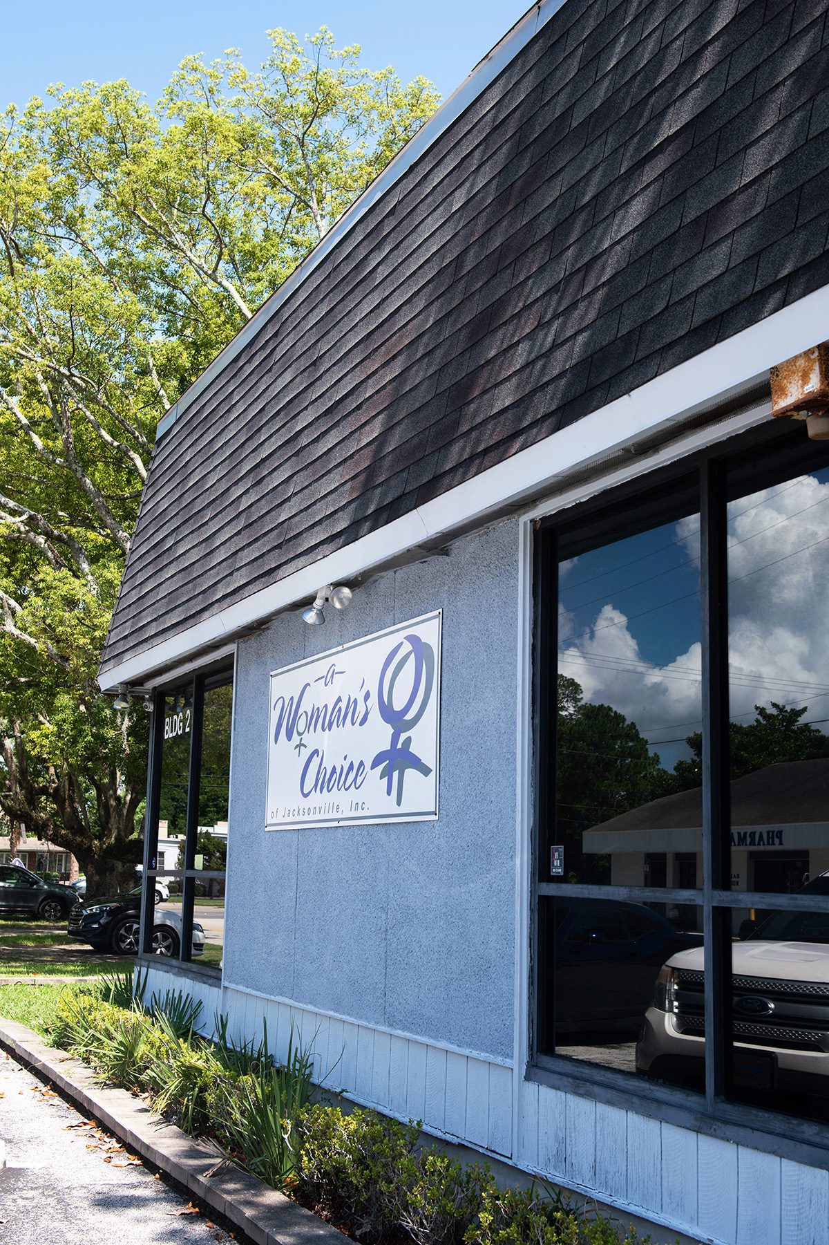 The entrance of a Woman's Choice in Jacksonville, a blue building with tinted windows.