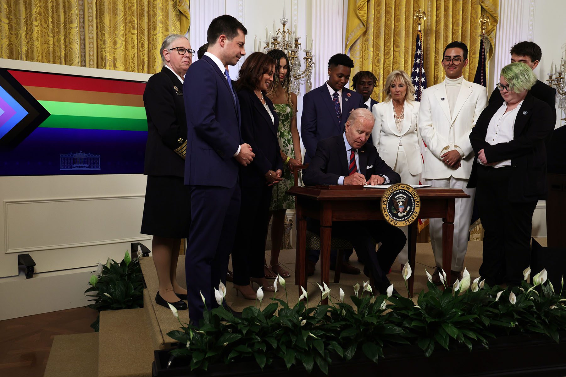 President Biden signs an executive order at a desk as others look on.