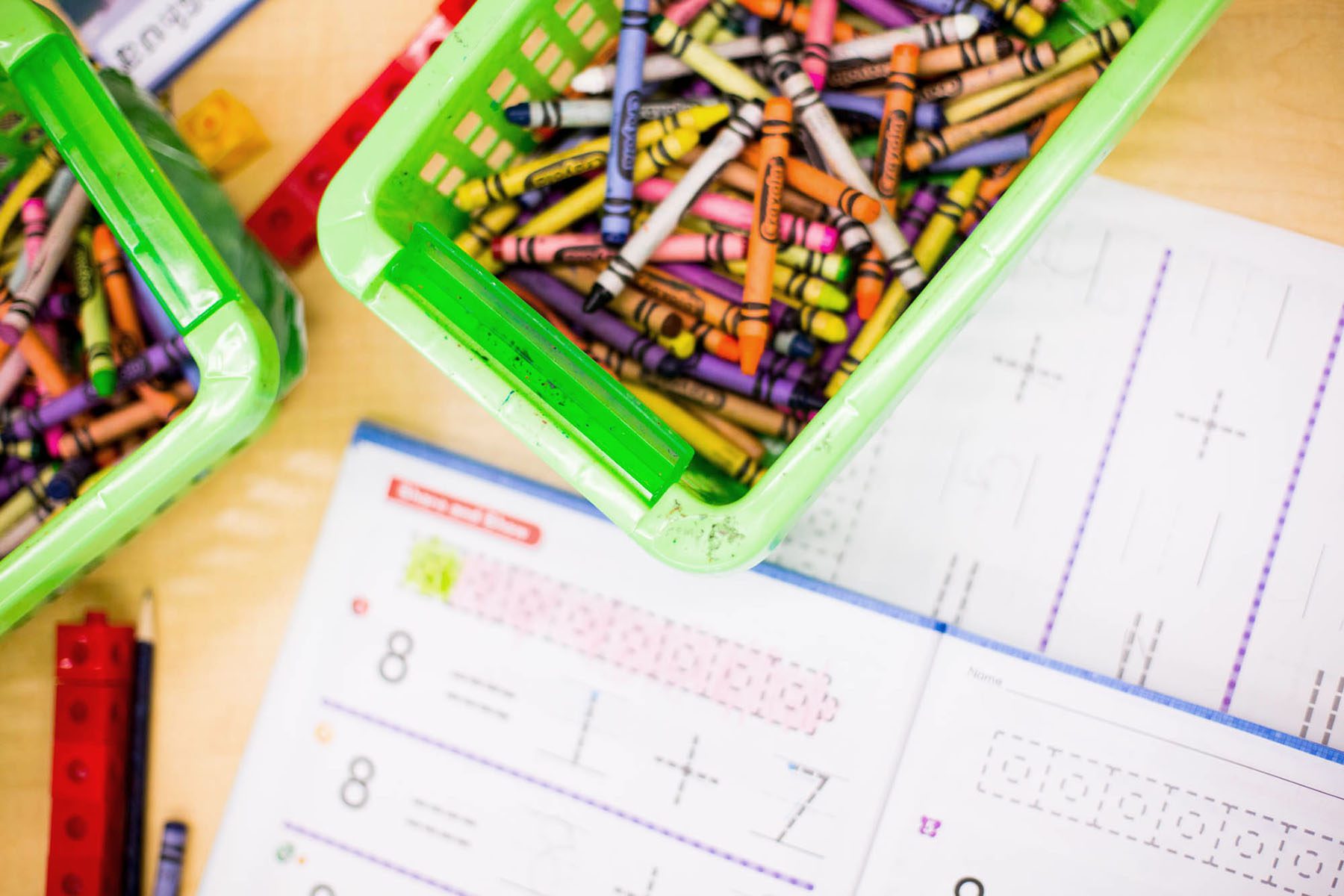 Color crayons and math exercise books are seen in a classroom